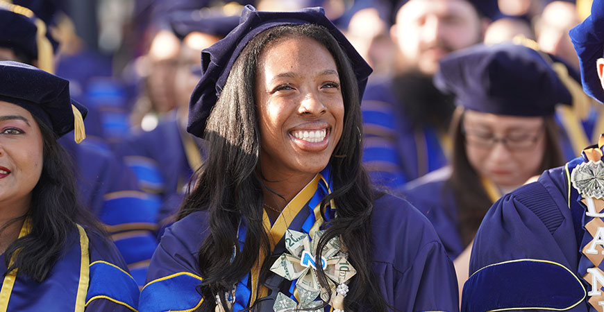 A graduate student eagerly anticipates her hooding ceremony.