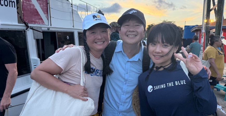 UC Merced Professor Sora Kim stands on a dock next to actor and comedian Ken Jeong and singer and rapper Rei Ami. 